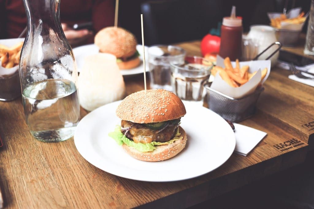 A cheeseburger on a white plate on a restaurant table