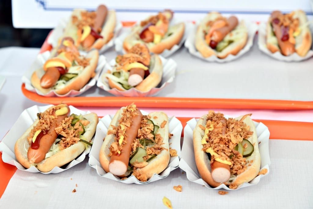 A tray of hot dogs topped with crispy onions and pickles in paper boats