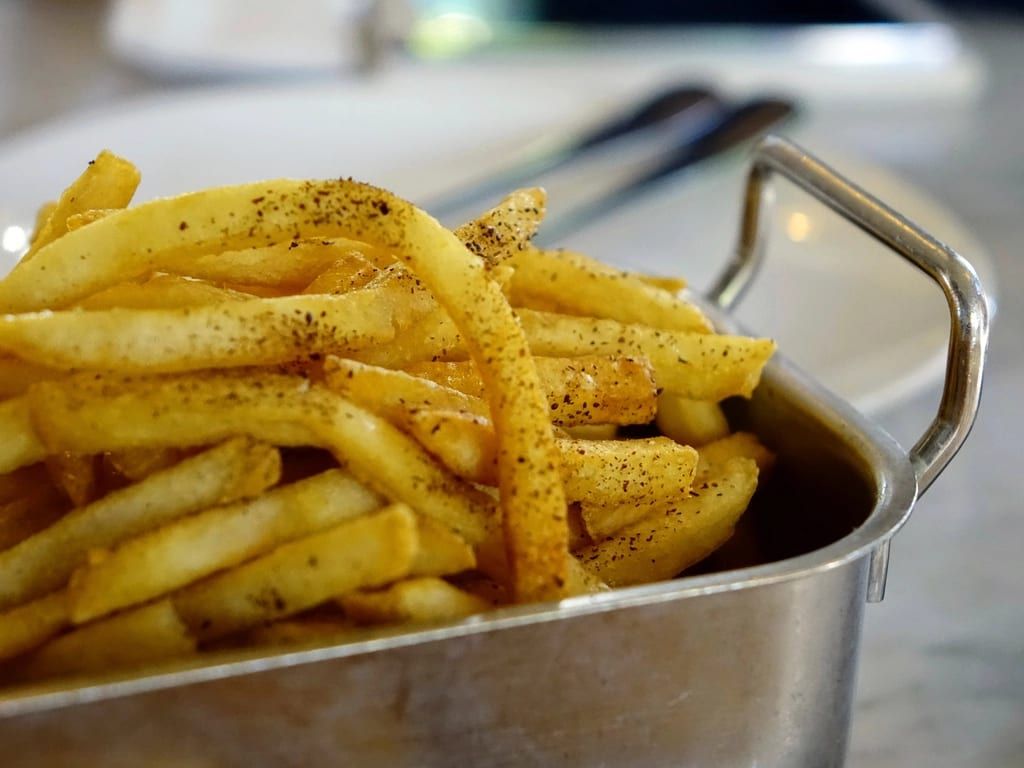 Seasoned fries piled in a metal serving tray